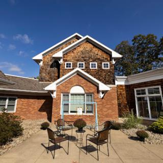 A beautiful multi-story house featuring a mix of brick and wooden elements, surrounded by a landscaped garden.