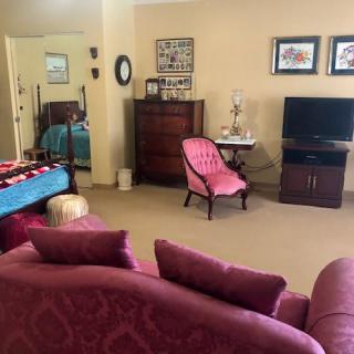 A cozy living room with pink furniture and a TV setup.