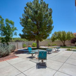 A sunny backyard patio area with outdoor furniture and trees.