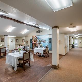 A cozy dining area with neatly arranged tables and chairs, illuminated by overhead lighting.