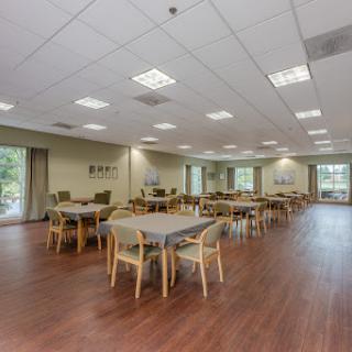 A spacious, well-lit dining area featuring multiple tables and chairs, designed for communal use.