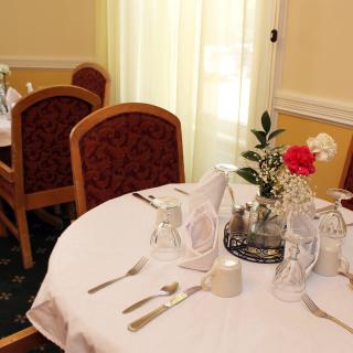A dining table set with formal place settings and a floral centerpiece.