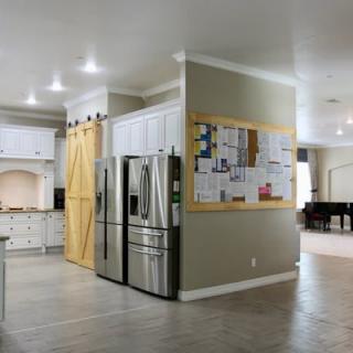 A modern kitchen with a stainless steel refrigerator, barn doors, and a bulletin board on the wall.