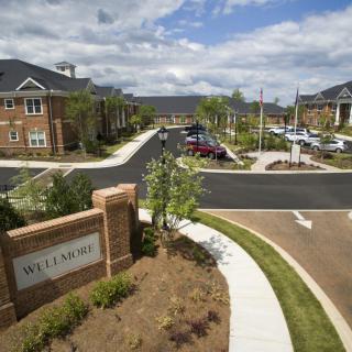 A suburban residential complex with well-maintained landscaping and a visible entrance sign.