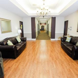 A spacious lobby area with leather sofas, a chandelier, and a hallway leading further into the building.