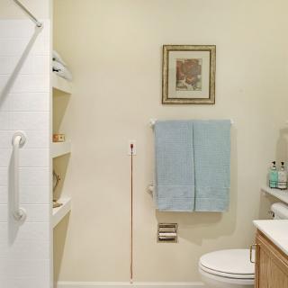 A neatly organized bathroom with a towel rack, shelving, and simple decor.