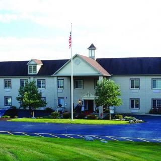 A two-story building with a neatly landscaped exterior, featuring a flagpole and clear blue sky.