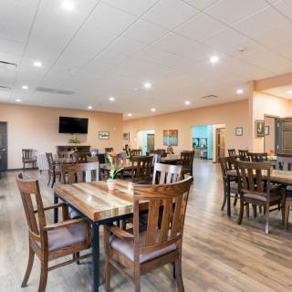 A spacious and well-lit dining area with wooden tables and chairs, designed for a comfortable dining experience.