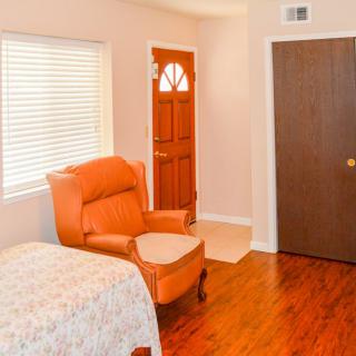A cozy bedroom with an armchair, wooden door, and a window.