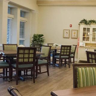 A cozy dining area with green-upholstered chairs and wooden tables, accented by decor and plants.