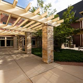 A courtyard featuring a pergola and landscaping with trees.
