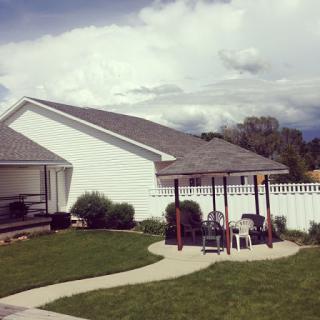 A serene backyard setting featuring a play area, well-kept lawn, and distant clouds.