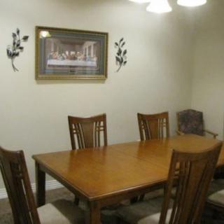 A dining room with a wooden table, six chairs, wall art, and overhead lighting.