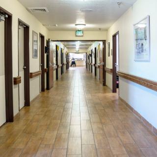 A clean and empty hallway in a nursing home with doors on each side.