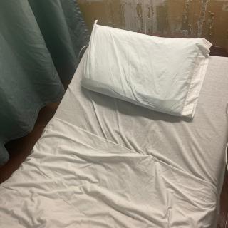 A neatly made bed with a white pillow and sheets in a room.