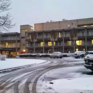 A snow-covered parking lot in front of a lit-up building during winter.