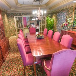 Elegant dining room with pink chairs and a wooden table.