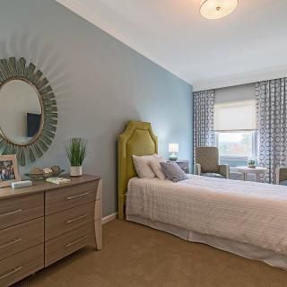 A cozy bedroom featuring a single bed, modern furnishings, and soft neutral tones.