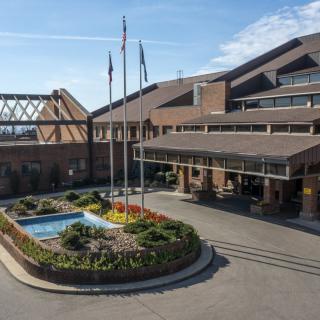 A hotel entrance with flags and a landscaped area featuring a fountain.