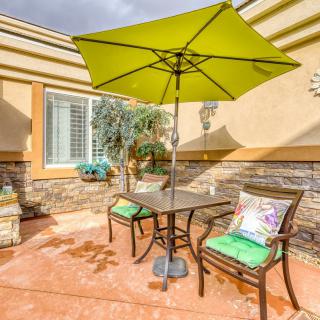 A sunny patio with a green umbrella, two chairs, and a table.
