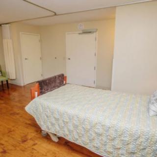 A minimalist bedroom with a single bed and wooden flooring.