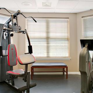 A well-equipped gym with exercise machines and a bench in a bright workout room.