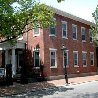 A historic brick building on a tree-lined street.