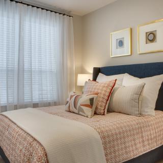 A cozy bedroom with neatly arranged pillows, soft lighting, and elegant decor.