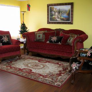 A cozy living room with red sofas, ornate pillows, and a decorative rug.