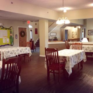 A cozy dining area with neatly arranged tables and chairs, decorated with warm lighting.