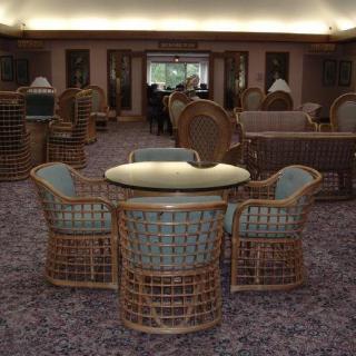 A cozy indoor lounge area featuring rattan chairs and a glass-top table.