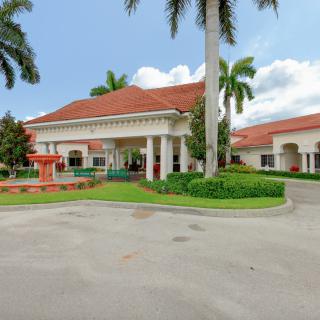 A beautiful entrance to a tropical-style building with red roofs and lush landscaping.