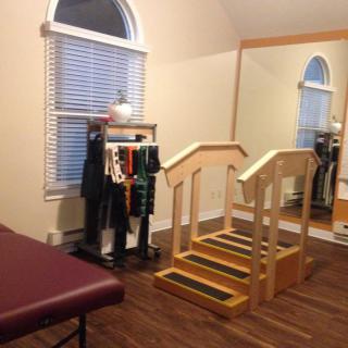A therapy room equipped with a set of stairs, a treatment table, and various exercise tools for rehabilitation.
