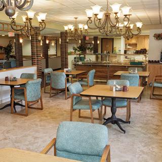 A cozy and inviting restaurant interior with neatly arranged tables and chairs, illuminated by elegant chandeliers.