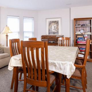 A cozy dining room with wooden furniture and a bookshelf filled with games and books.