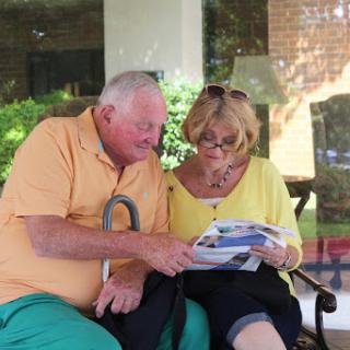 A senior couple enjoying a moment together while reading outdoors.