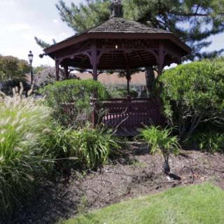 A wooden gazebo surrounded by lush greenery in a garden setting.