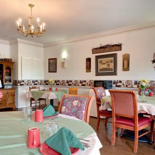 A cozy dining room with elegantly set tables and a chandelier.