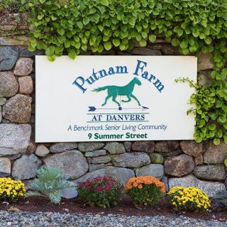 Putnam Farm at Danvers sign displayed on a stone wall with surrounding flowers and greenery.
