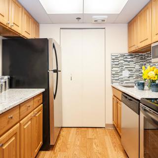 A modern kitchen with wooden cabinets, stainless steel appliances, and a decorative backsplash.