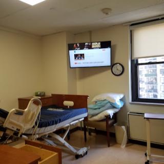 A view of a hospital room equipped with a patient bed and a television mounted on the wall.