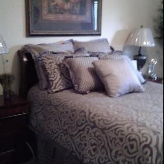 A neatly arranged bedroom with decorative pillows and an elegant lamp.