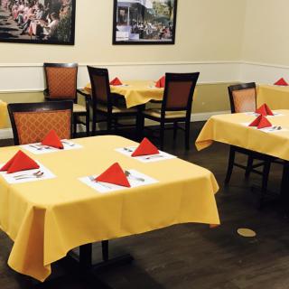 A neatly arranged restaurant dining area featuring tables with yellow tablecloths and red napkins.