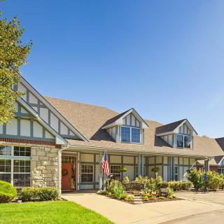 A large residential house with a gable roof and well-maintained front yard on a sunny day.