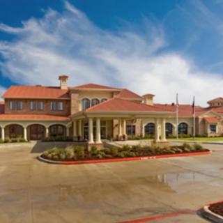 A large hotel building with a red-tiled roof and arched windows under a blue sky with clouds.