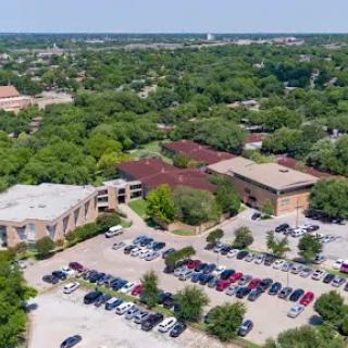 A beautiful aerial view of a school campus surrounded by lush greenery and a packed parking lot.