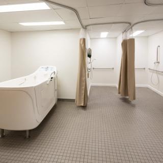 A clean, modern medical bathroom with a bath and privacy curtains.