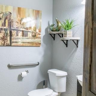 A stylish and modern bathroom featuring decorative shelves, wall art, and a touch of greenery.