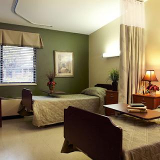 A serene patient room equipped with twin beds, a nightstand, and natural light filtering through the window.