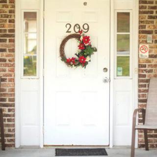 A decorated front door with a holiday wreath and brick exterior.